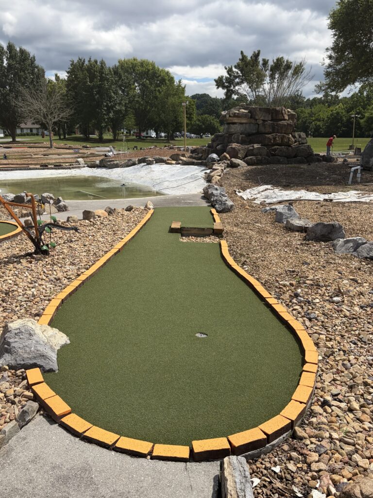 mini golf pad with yellow bricks and water