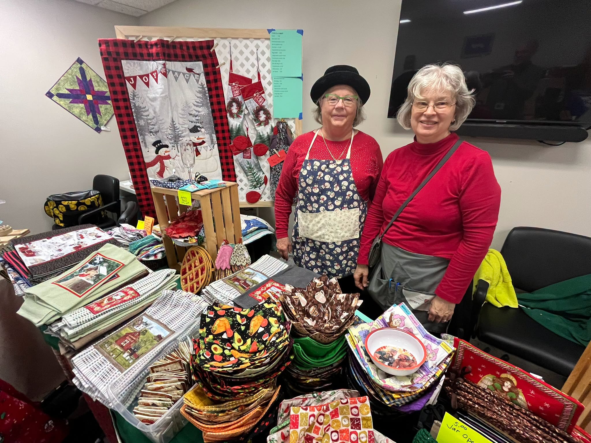 Two crafters stand with their booth of fabric goods at a previous fair.